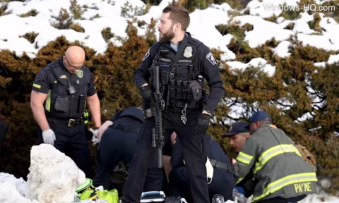 Officers in tactical gear and uniformed personnel standing outdoors next to snow-covered objects.
