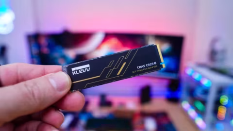 A hand holding a black solid-state drive (SSD) labeled KLEVV CRAS C925G.