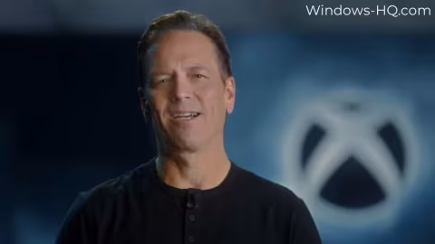 A middle-aged man with graying hair standing in front of a backdrop displaying the Xbox logo.