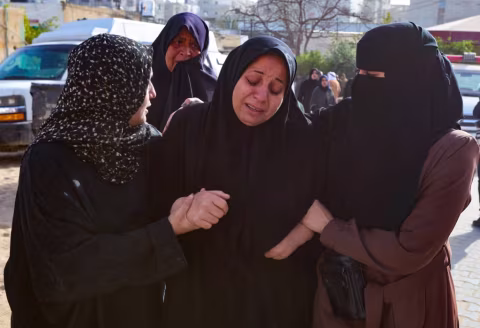 Five women gather together outdoors, engaged in conversation.