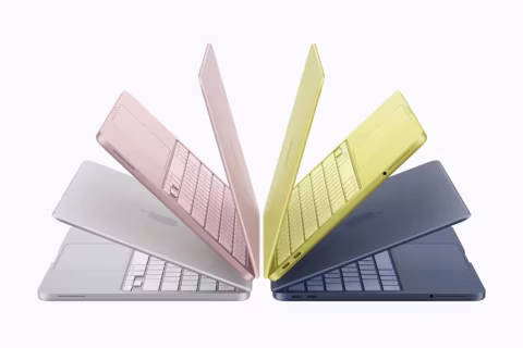 A collection of five laptops in various colors arranged on a white background.