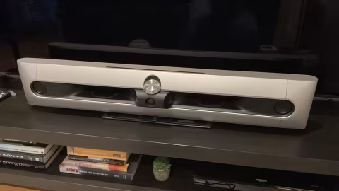Silver soundbar audio device resting horizontally on a flat surface.