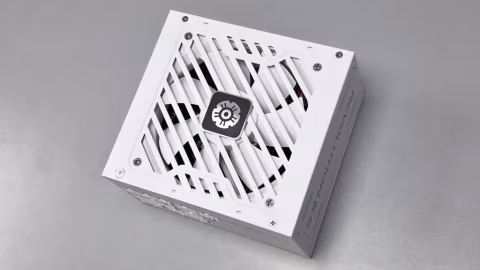 A white, square power supply unit with a circular fan in the center, resting on a gray surface.