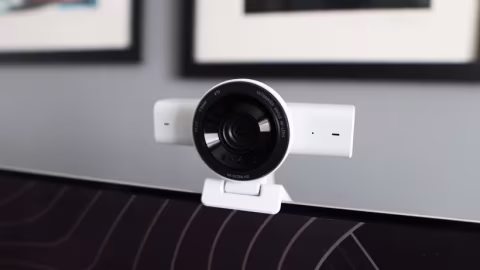 Small, white external camera attached to a stand, placed on a dark, patterned surface.