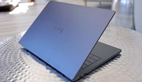 Open laptop displaying the XPS logo, sitting on a textured white surface.