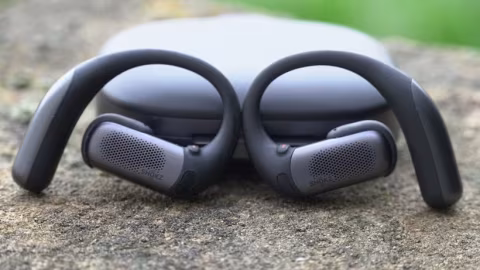 Black open-ear headphones resting on a textured, gray surface.