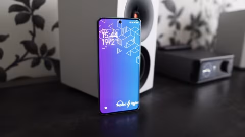 Smartphone displaying a bright blue background with geometric patterns and a clock showing 15:44.