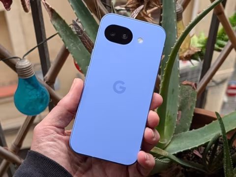 Hand holding a light blue smartphone with a white camera module and a Google logo.