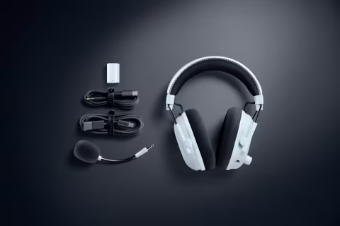White gaming headset, microphone, and charging cables arranged on a dark background.