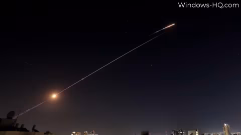 Two bright streaks of light cross a dark night sky above a skyline.
