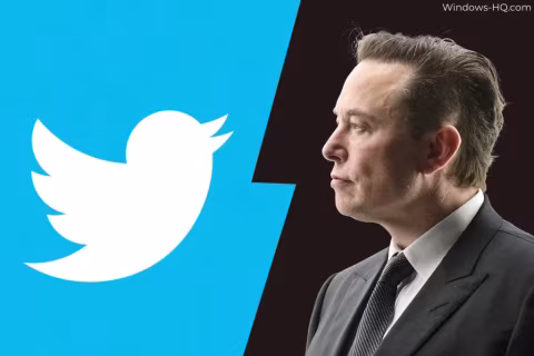 A man in a suit stands next to the Twitter logo on a blue background.