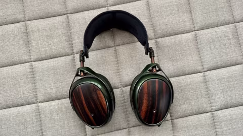 A pair of over-ear headphones with wooden accents resting on a light gray textured surface.