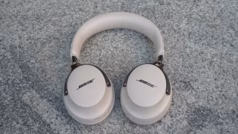 A pair of white over-the-ear headphones resting on a gray, textured surface.