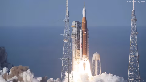 A large rocket launching from a launchpad over the ocean.