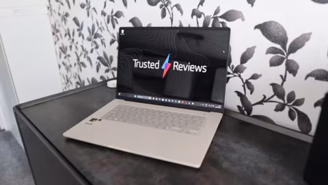 A silver laptop computer open on a dark surface, displaying a webpage with the text "Trusted Reviews".