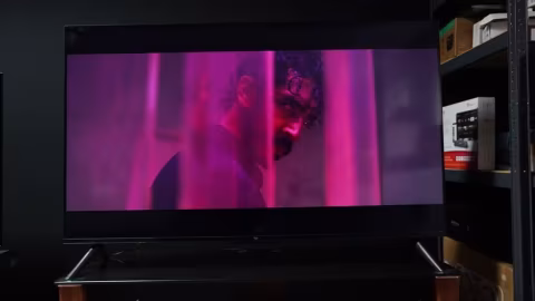 Screenshot of a television displaying a close-up of a man's face in colorful lighting.