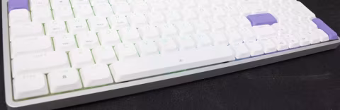 A low-profile mechanical keyboard with white keycaps and purple accent keys.