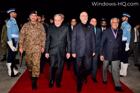 Group of men in suits and formal wear standing on a red carpet indoors.