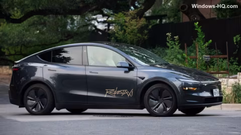 Dark gray Tesla Model X parked on a paved street with landscaping visible in the background.