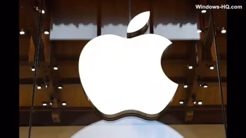 A large white apple logo mounted on a pedestal against a wooden architectural backdrop.