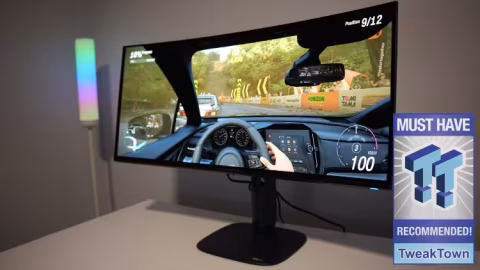 Curved computer monitor displaying a simulated vehicle dashboard interface with digital gauges and metrics.