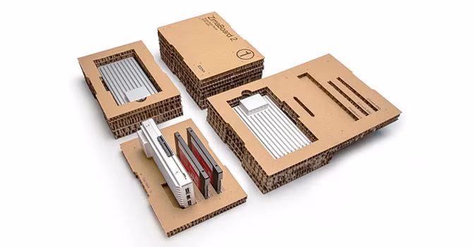 A collection of circuit boards, connector strips, and labeled packaging materials are arranged on a white surface.