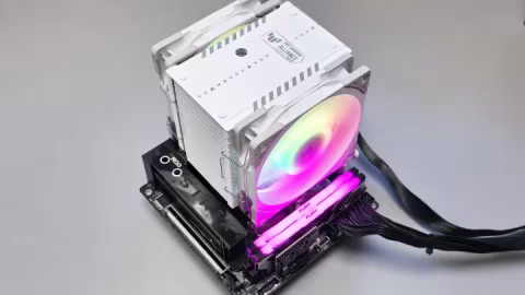 Large white CPU cooler featuring a translucent, multi-colored fan resting on a plain gray surface.