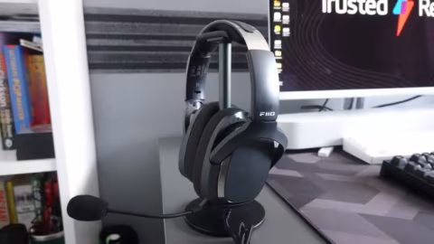 Black over-ear gaming headset resting on a desk next to a computer monitor.
