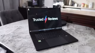 Open laptop displaying 'Trusted Reviews' text and logo on the screen, resting on a light gray marble surface.