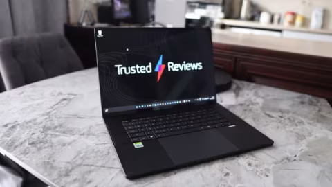 Open laptop displaying 'Trusted Reviews' text and logo on the screen, resting on a light gray marble surface.
