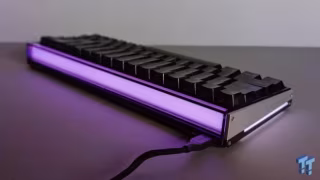 Rectangular mechanical keyboard illuminated with bright purple light, resting on a dark surface.