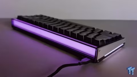 Rectangular mechanical keyboard illuminated with bright purple light, resting on a dark surface.