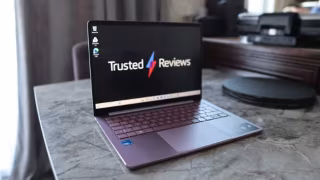 A laptop displaying the 'Trusted Reviews' logo, resting on a textured gray surface.