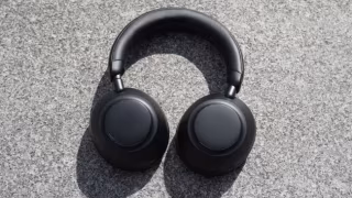 A pair of black over-ear headphones resting on a textured gray background.