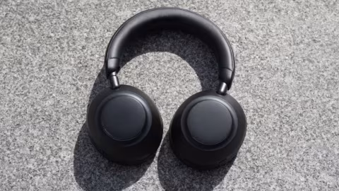 A pair of black over-ear headphones resting on a textured gray background.