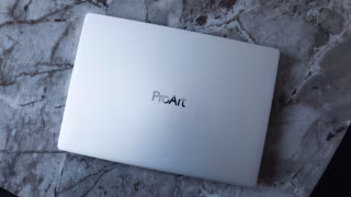A light-colored laptop closed on a marbled surface, featuring the ProArt logo on the lid.